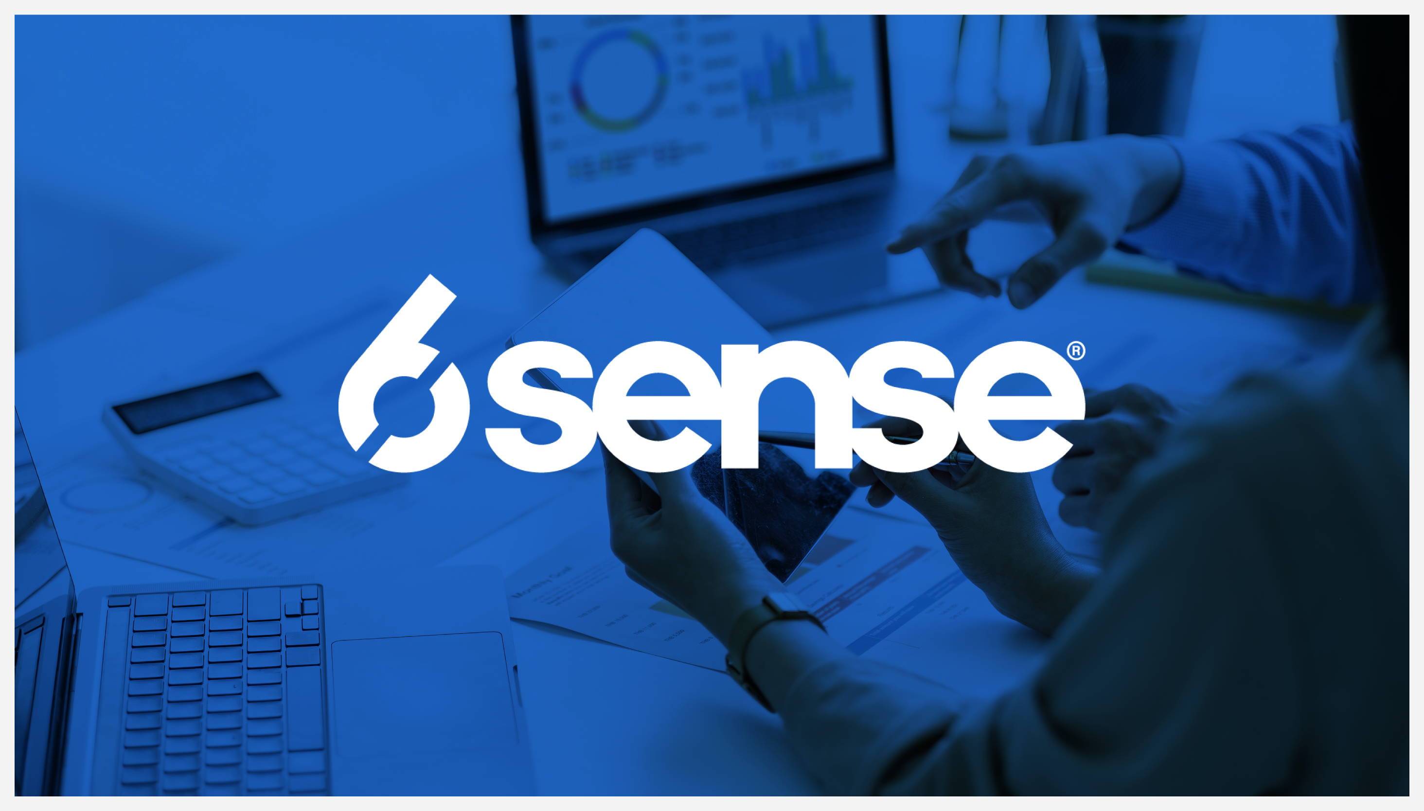 6sense logo overlapping a photograph of two revenue professionals looking at reports in front of two laptops