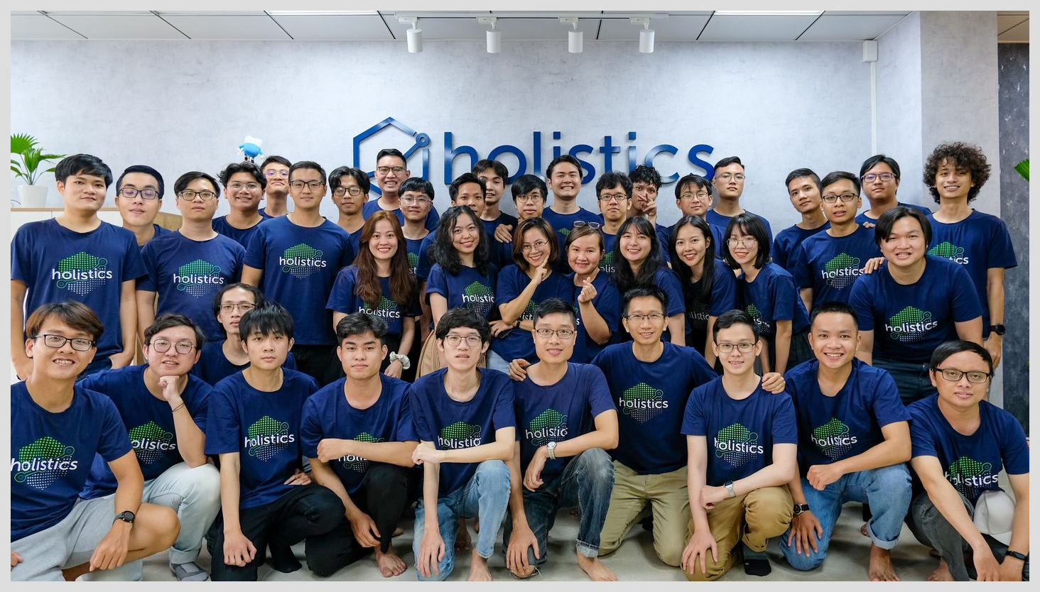 Holistics team members in front of the Holistics sign