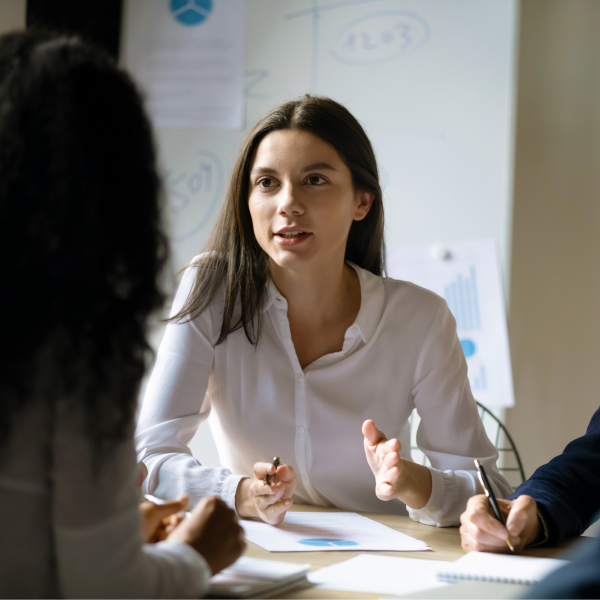 Photograph of a customer success/post-sales professional talking to two customers at a conference table